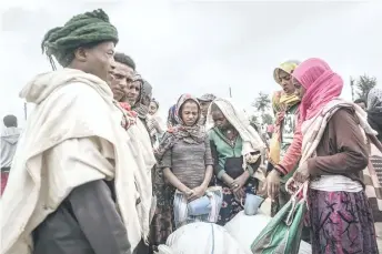  ?? — AFP photos ?? People who fled the war from May Tsemre, Addi Arkay and Zarima gather around in a temporaril­y built internally displaced people (IDP) camp to receive their first bags of wheat from the World Food Programme (WFP) in Debark, 90 kilometres of the city of Gondar, Ethiopia.