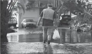  ?? PHOTOS BY ERIC ROJAS / THE NEW YORK TIMES FILE (2017) ?? Chef José Andrés walks through water Oct. 19, 2017, to deliver dinner to a 91-year-old veteran in Loíza, Puerto Rico. The James Beard award-winning chef recounts his experience­s in Puerto Rico in the aftermath of Hurricane Maria in his new memoir, “We Fed an Island: The True Story of Rebuilding Puerto Rico, One Meal at a Time.”