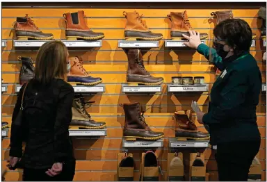  ?? (AP) ?? An employee helps a customer shop for Bean Boots last month at the L.L. Bean flagship retail store in Freeport, Maine. Retail sales surged a seasonally adjusted 9.8% in March, the Commerce Department said Thursday.