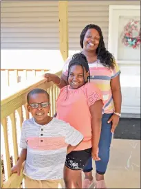  ?? STACI VANDAGRIFF/RIVER VALLEY & OZARK EDITION ?? Amber Robinson and her two children, Kai, 7, left, and Nevaeh, 8, stand in front of their home in Russellvil­le. After being homeless four years ago, Amber earned a new home through Habitat of Humanity of Pope County, and she and her children moved in earlier this month.