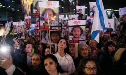  ?? Photograph: Amir Levy/Getty Images ?? People hold photos of hostages on Saturday in Tel Aviv during a rally to mark 100 days of captivity at the hands of Hamas in Gaza.