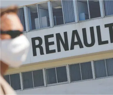  ?? STEPHANE MAHE / REUTERS ?? An employee on strike, wearing a protective face mask, is seen in front the Fonderie de Bretagne plant, a subsidiary
of Groupe Renault, during a blockage to protest against its possible closure in Caudan, France, on Monday.