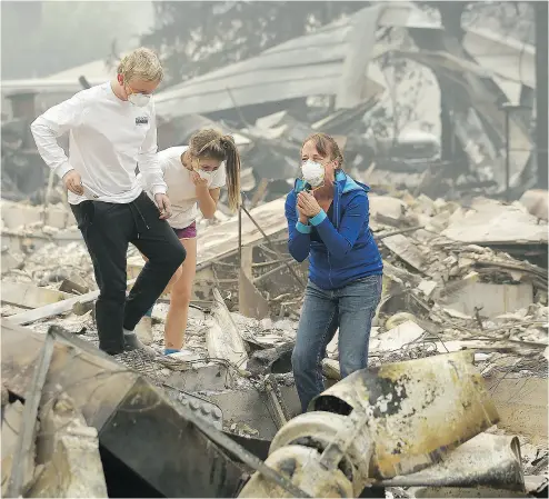  ?? JEFF CHIU / THE ASSOCIATED PRESS ?? Mary Caughey, centre, reacts with her son Harrison, left, after finding her wedding ring Tuesday in the mangled, burned debris of her Kenwood, Calif., home after wildfires raced through the area.
