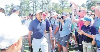  ?? — AFP photo ?? Woods (centre) walks to the first tee during a practice round prior to the Masters at Augusta National Golf Club in Augusta, Georgia.