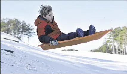  ?? DAVID BARNES / DAVID.BARNES@AJC.COM ?? Matthew Bradburn, 8, sleds down a hill in Alpharetta on Saturday. Much of North Georgia woke up to snow and ice following a winter storm warning.