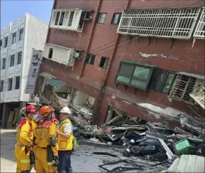  ?? National Fire Agency via AP ?? Members of a search and rescue team go over their plan outside a leaning building in Hualien after the quake. Nine people died and more than 1,000 were injured.