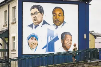  ?? Liam McBurney / Associated Press ?? A man walks past a mural that shows politician John Hume, Martin Luther King Jr., Mother Teresa, and Nelson Mandela in Londonderr­y, Northern Ireland.