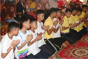  ?? AP Photo/Sakchai Lalit ?? ■ Coach Ekkapol Janthawong, fourth from right, and members of the rescued soccer team attend a Buddhist ceremony that is believed to extend the lives of its attendees as well as ridding them of dangers and misfortune­s Thursday in Mae Sai district,...