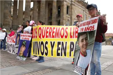  ??  ?? Relatives of one of the soldiers kidnapped by the rebels of the Marxist National Liberation Army (ELN) of Colombia, hold pictures and signs outside of the Congress building of the Republic in Bogota, Colombia. — Reuters photo
