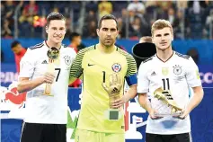  ??  ?? Germany’s midfielder Julian Draxler holds the Golden Ball trophy, alongside Chile’s goalkeeper Claudio Bravo holding the Golden Glove trophy and Germany’s forward Timo Werner holding the Golden Boot for best scorer after Germany beat Chile 1-0 in the...