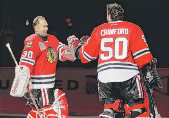  ??  ?? Former Blackhawks goaltender Ed Belfour greets Corey Crawford while being honored before the game Thursday against the Stars at the United Center. | GETTY IMAGES