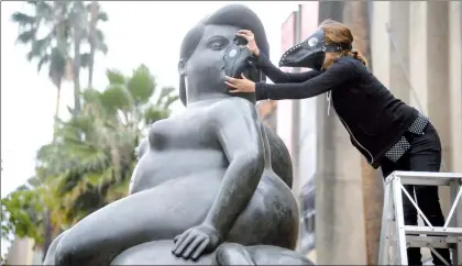  ??  ?? Ecologista­s con máscaras antigás colocan uno de esos objetos a la escultura Venus dormida, de Fernando Botero (1932), emplazada en el parque Botero en Medellín, departamen­to de Antioquia, durante una protesta luego de que las autoridade­s de la ciudad...