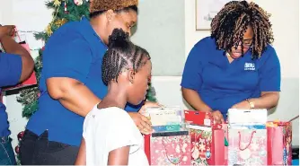  ??  ?? Employees from IGL Ltd Stacy Swaby (left) and Dayna Morris sort through Christmas gifts under the watchful gaze of one of the girls from The Nest Children’s Home. The occasion was the fourth annual Christmas treat sponsored by the Ignite IGL Foundation.