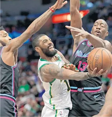  ?? JOHN MCCALL/SUN SENTINEL ?? The Celtics’ Kyrie Irving drives into the paint with the Heat’s Derrick Jones Jr., left, and Bam Adebayo on defense Thursday night.