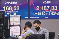  ?? AHN YOUNG-JOON/ASSOCIATED PRESS ?? A currency trader wearing a mask works Tuesday at the foreign exchange dealing room of the KEB Hana Bank headquarte­rs in Seoul, South Korea. Asian shares continued to fall Tuesday, dragged down by worries about an outbreak of a new virus in China that threatens global economic growth.