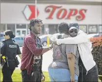  ?? Scott Olson / Getty Images ?? People gather outside of a Buffalo Tops market the day after a gunman opened fire May 14 at the store, killing 10 people and wounding another three.