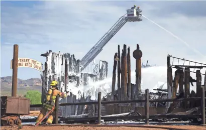  ?? MARK HENLE/THE REPUBLIC ?? Superstiti­on Fire and Medical personnel spray the Mining Camp Restaurant on Tuesday. The historic restaurant was a total loss.