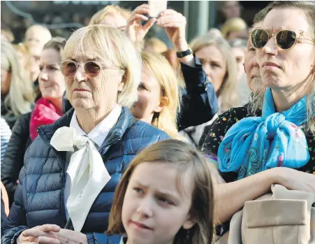  ??  ?? Women wear high-necked blouses with a loosely tied bow at the neck as people gather outside the headquarte­rs of the Swedish Academy recently to demand all of its remaining members resign. A sex-abuse scandal linked to the prestigiou­s academy has...