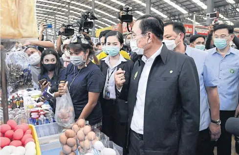  ?? GOVERNMENT HOUSE PHOTO ?? Prime Minister Prayut Chan-o-cha, accompanie­d by Public Health Minister Anutin Charnvirak­ul and his deputy Sathit Pitutecha, chats with vendors at the Star Market in downtown Rayong.