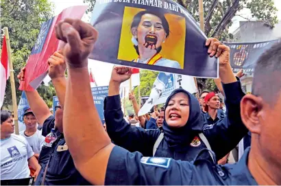  ?? AP ?? A woman raises slogans as she holds up a poster bearing a defaced portrait of Myanmar’s de facto ruler Aung San Suu Kyi during a rally against the persecutio­n of Rohingya Muslim minority, outside the Myanmar’s Embassy in Jakarta, Indonesia, on Monday—