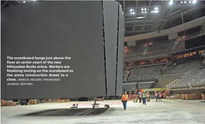  ?? JAMES B. NELSON / MILWAUKEE JOURNAL SENTINEL ?? The scoreboard hangs just above the floor at center court of the new Milwaukee Bucks arena. Workers are finalizing testing on the scoreboard as the arena constructi­on draws to a close.