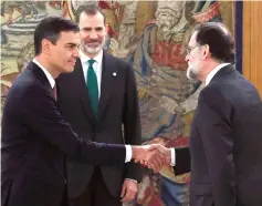  ??  ?? Sanchez (left) shakes hands with Rajoy (right) next to Spain’s King Felipe VI during the swearing-in ceremony at the Zarzuela Palace near Madrid. — AFP photo