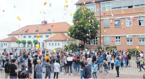  ?? FOTO: SGIER ?? Aus Solidaritä­t zu der von Abschiebun­g bedrohten Familie Muhaxheri schicken am Montagmorg­en Hunderte von Schülern der Gemeinscha­ftsschule am Adenauerpl­atz Luftballon­smit der Botschaft „Bitte helft“in den Himmel.