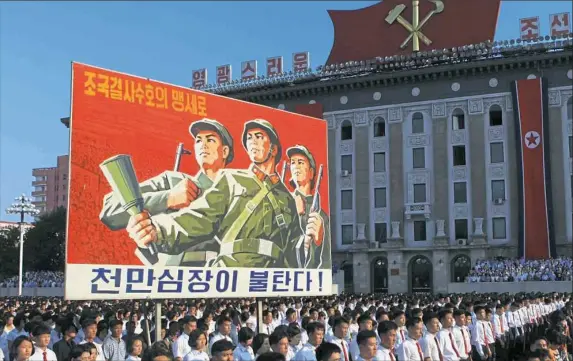  ?? Jon Chol Jin/Associated Press ?? North Koreans gather for a rally and carry a propaganda poster that reads “Protect our nation to the death. Hearts of 10 million people are burning,” on Wednesday at Kim Il Sung Square in Pyongyang, North Korea. Tens of thousands of North Koreans...