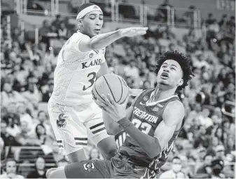  ?? Tony Gutierrez / Associated Press ?? Kansas’ Dajuan Harris Jr., left, tries to block a shot from Creighton guard Trey Alexander in the second half of their second-round matchup in Fort Worth.