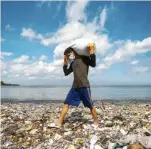  ??  ?? Filippine Un volontario ripulisce la spiaggia