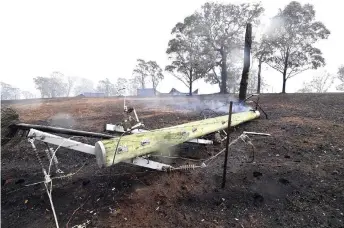  ??  ?? A smoulderin­g utility pole on the ground following bushfires in the outskirts of Quaama, New South Wales.