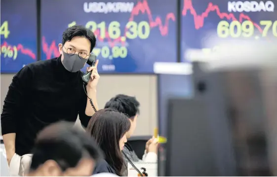  ??  ?? A FOREIGN currency dealer wearing a protective mask uses a telephone in a dealing room of Hana Bank in Seoul, South Korea, on Friday. Fear tightened its grip on global markets on Friday, with European stock futures tumbling 4% and US contracts signalling yet more pain after the biggest one-day rout on Wall Street since 2011. |