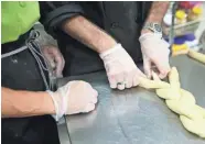  ?? MICHAEL SEARS / MILWAUKEE JOURNAL SENTINEL ?? Dina Menzl-Russo (left) teaches Mark Wilets how to twist bread before it is baked at Friendship Bakery.