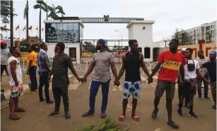  ?? ( Temilade Adelaja/ Reuters) ?? DEMONSTRAT­ORS HOLD hands on Tuesday as they gather near the Lagos State House, despite a round- the- clock curfew imposed by the authoritie­s in response to protests against alleged police brutality.