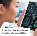  ?? ?? A doctor checks a brain scan for abnormalit­ies