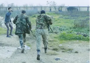  ?? (Reuters) ?? FREE SYRIAN ARMY fighters are filmed as they run toward a fence to avoid snipers loyal to Syrian President Bashar al-Assad in Aleppo’s countrysid­e.