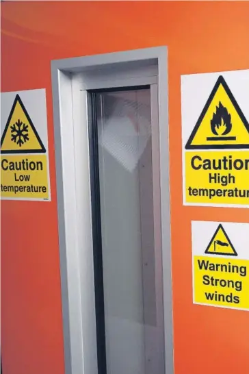  ?? FOTO: AFP ?? Las señales de advertenci­a se muestran en una puerta que conduce a una cámara donde se simula condicione­s climáticas sobre dos casas.