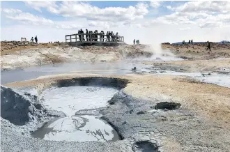  ??  ?? Visitors marvel at the steaming fumaroles and mud pots at Námafjall, a geothermal wonder.