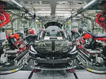  ?? Mason Trinca For the Washington Post ?? TESLA unsuccessf­ully argued that its Fremont plant was among those included in an exception for “critical infrastruc­ture sectors.” Above, robotic arms install seats in a Model 3 at the Tesla factory in 2018.