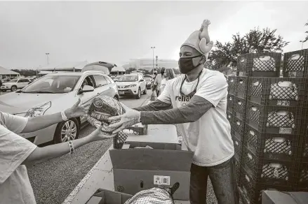  ?? Photos by Steve Gonzales / Staff photograph­er ?? Reliant employee Sidney Evan hands out frozen turkeys during the H-E-B Family Thanksgivi­ng Distributi­on at NRG Stadium on Saturday. The food distributi­on event was held in place of the annual Thanksgivi­ng Day parade.