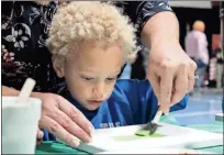  ?? Daniel Bell ?? Malachi Belk works on a painting with some assistance at the Boys and Girls Club during a Christmas celebratio­n.