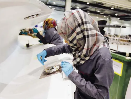  ??  ?? Jet-set industry: A woman technician applying final touches to a flap track fairing (FTF) at Strata, a composite aerostruct­ures manufactur­ing plant in Al Ain in Abu Dhabi. The factory is designed to help make lightweigh­t carbon jets that will open up...