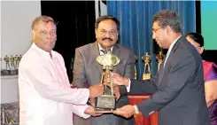  ??  ?? Narayanasa­my Gokulakris­hnan -Chairman / Managing Directorec­eiving the award from Minister Harsha De Silva. Director Sinnathamb­y Balasundar­am looks on