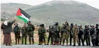  ?? Reuters ?? A demonstrat­or holds a Palestinia­n flag in front of Israeli troops in Jordan valley in the Israeli-occupied West Bank. —