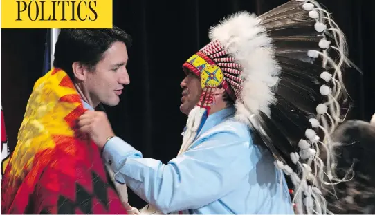  ?? ADRIAN WYLD / THE CANADIAN PRESS ?? AFN National Chief Perry Bellegarde adjusts a blanket presented to Prime Minister Justin Trudeau at the Assembly of First Nations Special Chiefs Assembly last December. Several chiefs had praised the Liberal government’s renewed commitment to indigenous affairs, while condemning the attitude of the bureaucrat­s they deal with.