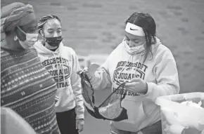  ?? ?? Fisher, right, and Mcnair, center, look for the right-sized bra for Nma Tambedu, 59, left, at the Church of the Good Shepherd Free Store.