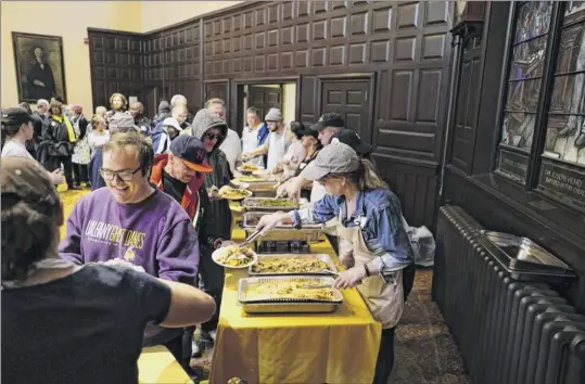  ?? Photos by Paul Buckowski / Times Union ?? Volunteers serve food at the Equinox Thanksgivi­ng Day community dinner Thursday at First Presbyteri­an Church in Albany. Some 4,000 volunteers make the annual dinner possible.