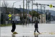  ?? ?? People walk through floodwater­s in Watsonvill­e on Saturday.