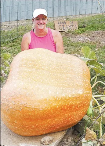  ?? Westside Eagle Observer/RANDY MOLL ?? Melissa Bond of Highfill poses behind a huge pumpkin she grew this growing season. The pumpkin's estimated weight. based on measuremen­ts. comes out to 454 pounds, but the exact weight won't be known until it is put on a scale. Bond said she planned to enter the pumpkin she named "Rosie" in the Benton County Fair this week.