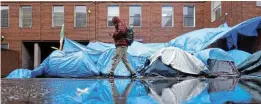  ?? Picture: REUTERS/ CLODAGH KILCOYNE ?? ROUGH LIVING: An asylum seeker walks past tents beside the Internatio­nal Protection Office in Dublin, Ireland, where hundreds of migrants in search of accommodat­ion have been sleeping on the streets for several months, with more arriving every day.